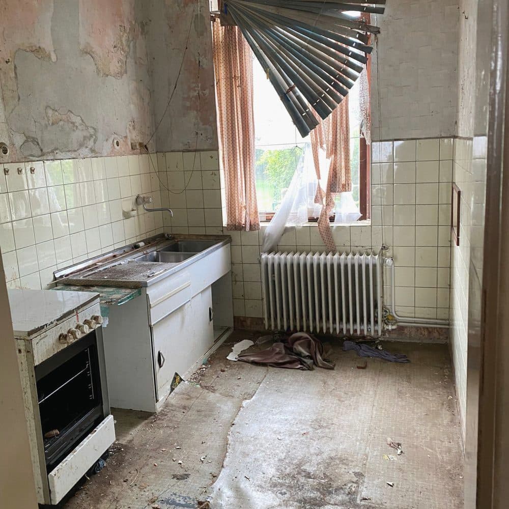 Alte Küche mit Spüle, Herd, Heizkörper und Fenster