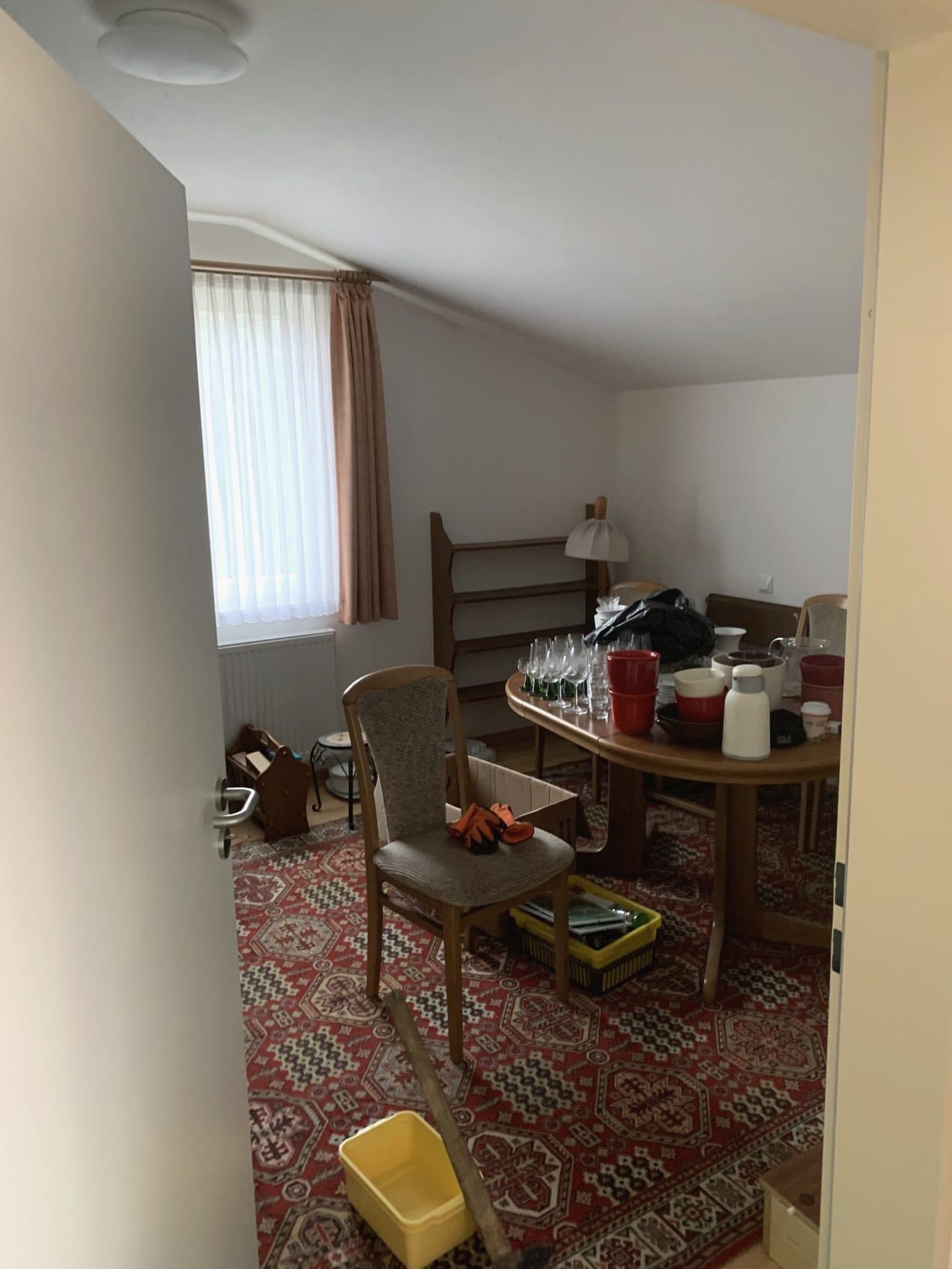 Dachzimmer vor der Räumung: Esstisch, Stühle, Regal und Teppich