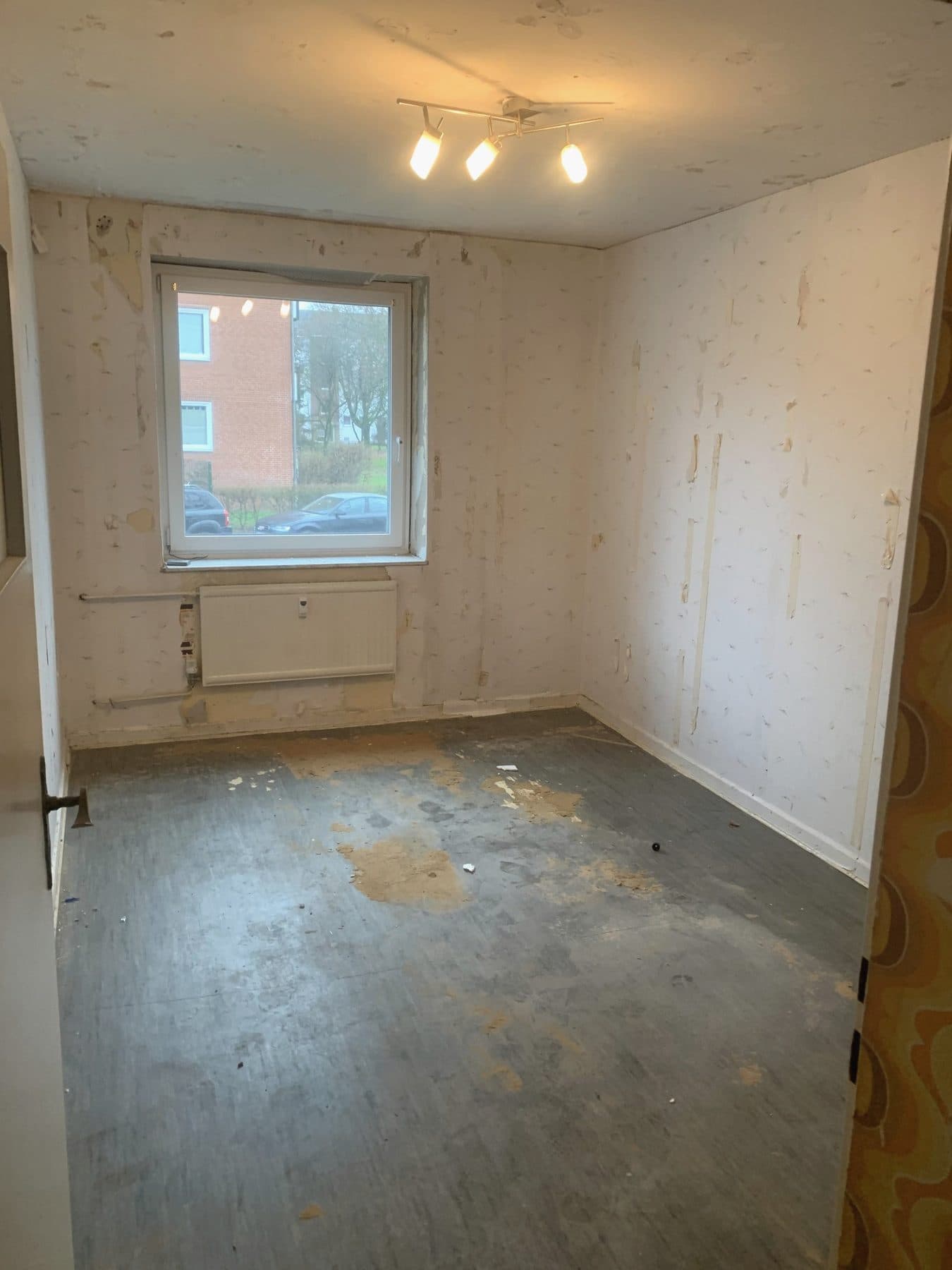 Zimmer nach einer Räumung: abgenutzter Bodenbelag und alte Tapete liegen frei