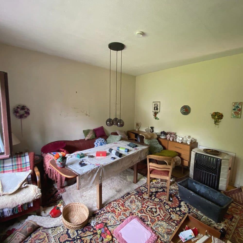 Wohnzimmer mit Esstisch, Kommode, Teppichen und Hausrat